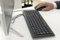 Male hand holds a mouse next to the keyboard and monitor of a personal computer on a white table. Close-up. A businessman, clerk, Royalty Free Stock Photo