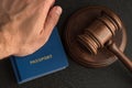 Male hand holds passport next to wooden gavel. Obtain citizenship. Legal immigration