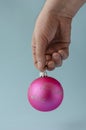 Male hand holds pink Christmas ball