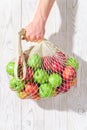 Male hand holds a string bag with red and green apples. Royalty Free Stock Photo