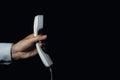 Male hand holds a telephone receiver. Photo on a black background. Royalty Free Stock Photo