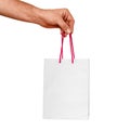 Male hand holds a white gift paper bag with red wicker handles, isolated Royalty Free Stock Photo