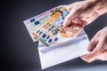 Male hand inserted into the envelope euro banknotes - bribe and corruption concept