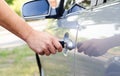 Male hand inserting a key into the door lock of a car