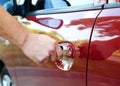 Male hand inserting a key into the door lock of a red car Royalty Free Stock Photo