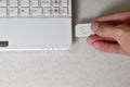 A male hand inserts a white compact SD card into the corresponding input in the side of the white netbook. Man uses modern techno