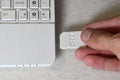 A male hand inserts a white compact SD card into the corresponding input in the side of the white netbook. Man uses modern techno
