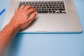 Male hand on a keyboard with blue background.