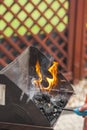 Male hand kindles fire in grill with long blue lighter. Man using BBQ lighter to start fire for charcoal in brazier. Royalty Free Stock Photo