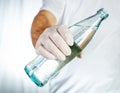 Male hand in latex glove holding glass bottle of water Royalty Free Stock Photo