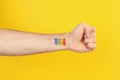 Male hand LGBT rainbow on yellow background, space for text