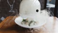 Male hand lifts to up glass cloche from a plate with hot food and moving smoke at the restaurant - Smoked food time! Close Up