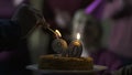 Male hand lighting candles on cake for 90 years old mother birthday, family care