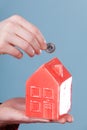 Male hand with little house and silver coin.