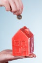 Male hand with little house and silver coin.