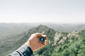 Male hand with magnetic compass high in mountains, pov. Royalty Free Stock Photo