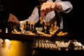 Male hand making move by white knight on chessboard in dark room Royalty Free Stock Photo