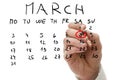 Male hand marking on calendar the date of March 8