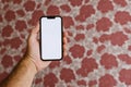 Male hand with mobile phone mockup, Man holding smartphone with blank mockup screen in home living room Royalty Free Stock Photo