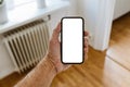 Male hand with mobile phone mockup, Man holding smartphone with blank mockup screen in home living room Royalty Free Stock Photo