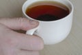 Male hand and a mug with tea on a beige surface