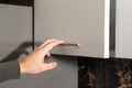 Male hand opening kitchen cupboard door Royalty Free Stock Photo