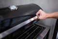 Male hand opening outdoor gas barbecue BBQ grill Royalty Free Stock Photo