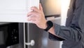 Male hand opening cabinet door in domestic kitchen Royalty Free Stock Photo