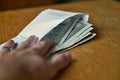 Male hand opening a white envelope full of American Dollars (USD, US Dollars) on the wooden table as a symbol of cash transfer, mo Royalty Free Stock Photo