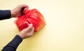 Male hand packing food trash with red plastic bag on color background.Recycle and environment concepts