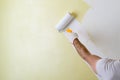 Male hand painting wall with paint roller. Painting new apartment renovating with yellow color paint Royalty Free Stock Photo