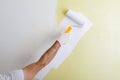 Male hand painting wall with paint roller. Painting new apartment renovating with yellow color paint Royalty Free Stock Photo