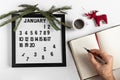 Male hand with a pen and a notebook for taking notes of goals and plans for the new year, calendar and Christmas tree decoration Royalty Free Stock Photo