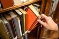 Male hand picking old book from bookshelf Royalty Free Stock Photo
