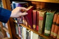 Male hand picking vintage book from bookshelf Royalty Free Stock Photo
