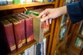 Male hand picking vintage book from bookshelf Royalty Free Stock Photo