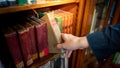 Male hand picking vintage book from bookshelf Royalty Free Stock Photo