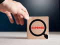Male hand places the wooden cubes with the word expense with a magnifying glass icon. Expense analysis Royalty Free Stock Photo