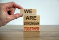 Male hand placing a block with word `we` on top of a blocks tower with words `are stronger together`. Wooden table. Beautiful Royalty Free Stock Photo