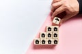 Male hand placing a protective umbrella icon on top of the wooden cubes with house icons. Real estate or house insurance