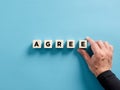 Male hand placing the wooden cubes with the word agree. To reach a business agreement