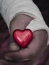 Male hand in plaster cast holding small glossy red heart. Royalty Free Stock Photo