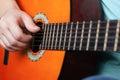 Male hand plays acoustic guitar strings. learning to play a musical instrument orange color close-up Royalty Free Stock Photo