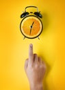 Male Hand Pointing Alarm Clock of Orange Fruit on Yellow Background Royalty Free Stock Photo