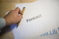 Male hand pointing at a forecast document printed on a white sheet of paper during a business meeting