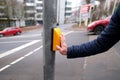 male hand presses a yellow device with a button on demand with a symbol of a man to cross the road in france, a pedestrian Royalty Free Stock Photo