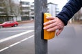 male hand presses a yellow device with a button on demand with a symbol of a man to cross the road in france, a pedestrian Royalty Free Stock Photo