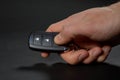 Male hand pressing a button on a car key remote control on the black background Royalty Free Stock Photo