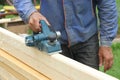 The male hand processes a wooden board an electric planer