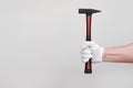 Male hand in protective white glove holding red hammer isolated on white background. House or car repair and renovation, Royalty Free Stock Photo